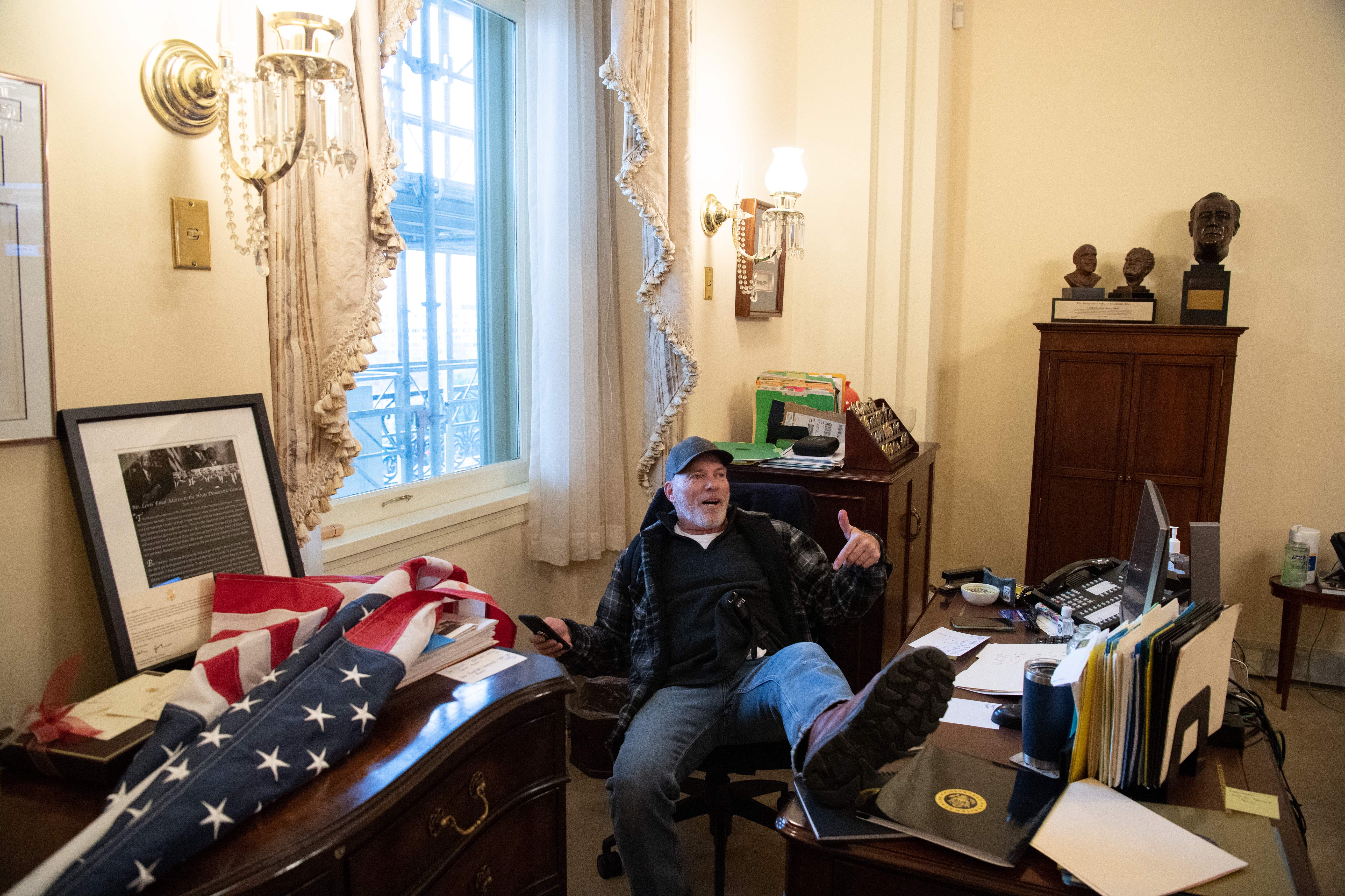 A supporter of US President Donald Trump sits inside the office of Speaker of the House Nancy Pelosi.