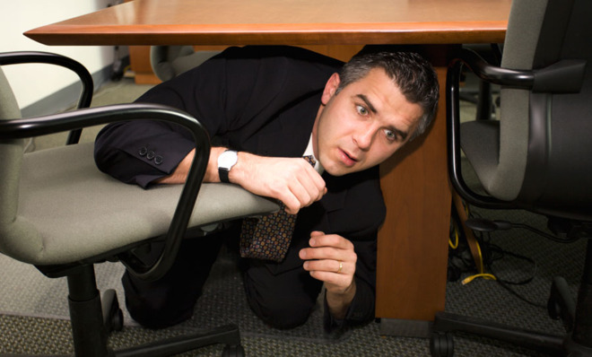 Man hiding under desk