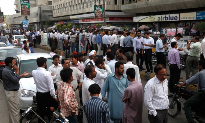 People stand outside their office buildings following an earthquake tremor in Karachi, Pakistan, on April 16.