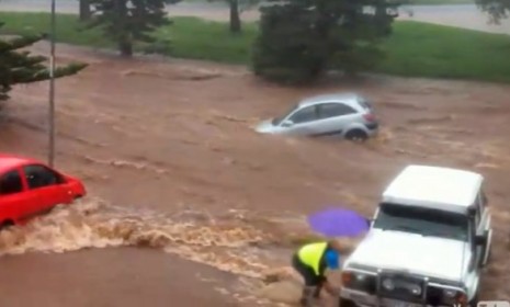 One man attempts to move his car while the rushing water takes away other cars parked nearby. 