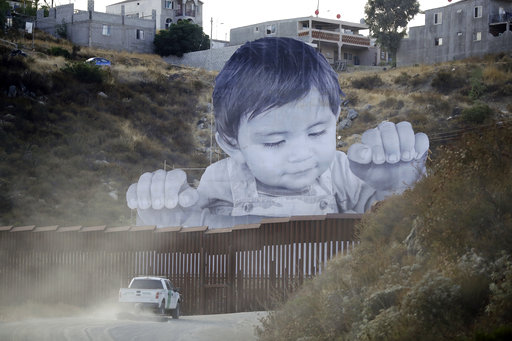 A Border Patrol vehicle drives in front of a mural in Tecate, Mexico, just beyond a border structure Friday, Sept. 8, 2017, in Tecate, Calif.