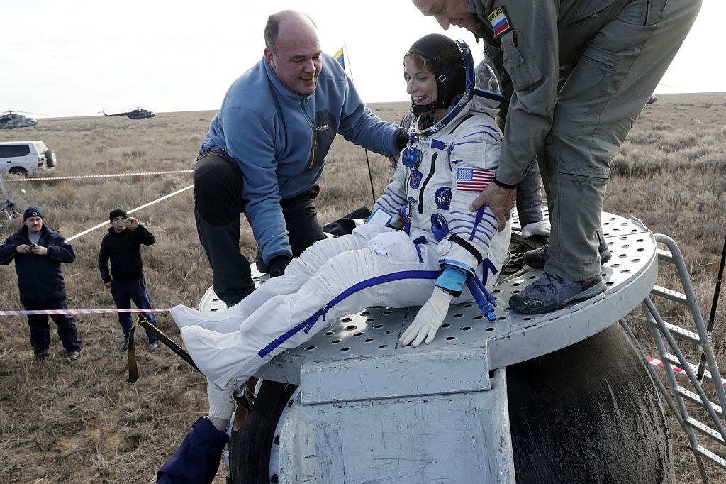 Ground personnel help astronaut Kate Rubins get out of the Soyuz space capsule 