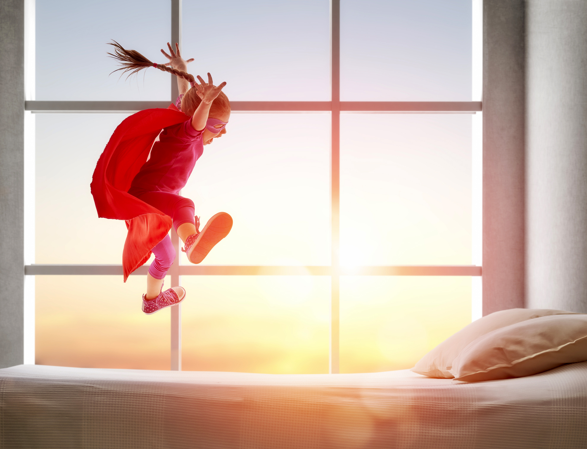 A girl jumping on a bed.