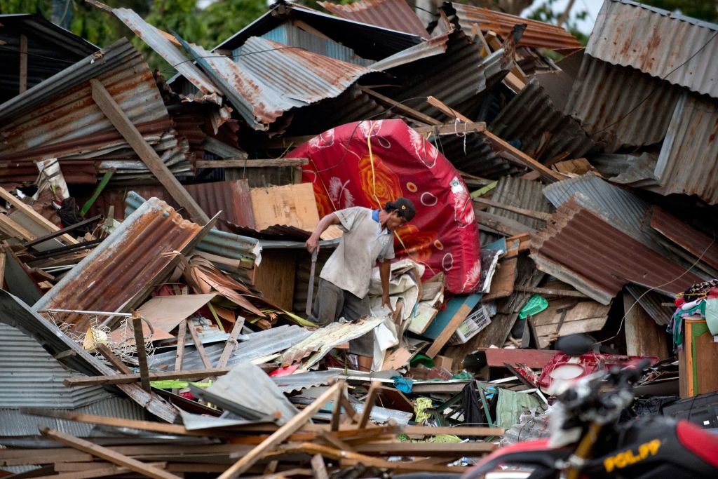 A man looks for his belongings amid the debris of his destroyed house in Palu in Central Sulawesi on September 29, 2018, after a strong earthquake and tsunami struck the area. 
