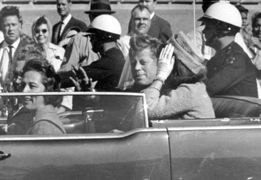 President John F. Kennedy waves from his car in a motorcade in Dallas