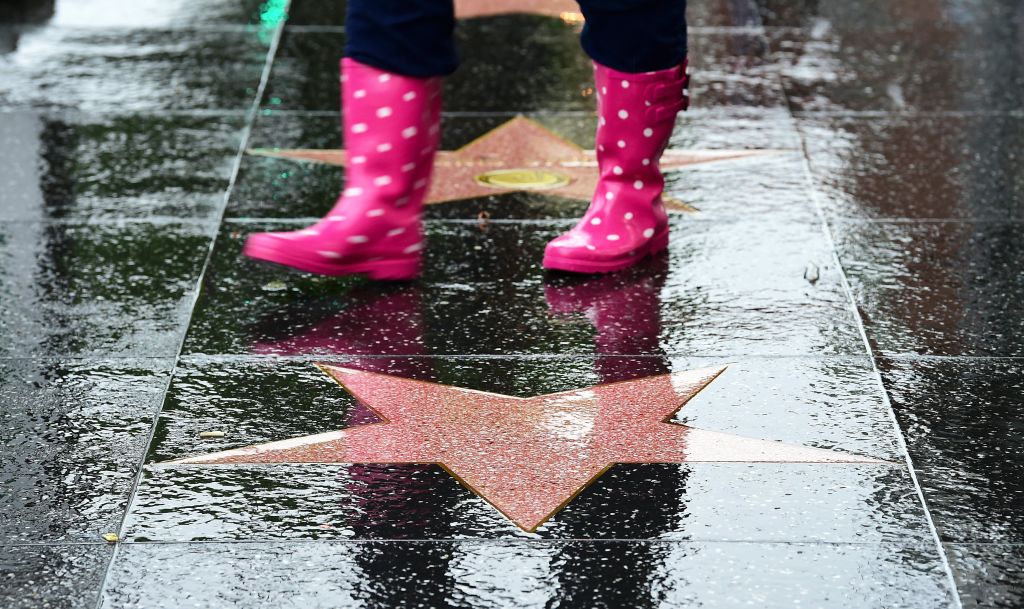 A person walks in the rain along the Hollywood Walk of Fame.