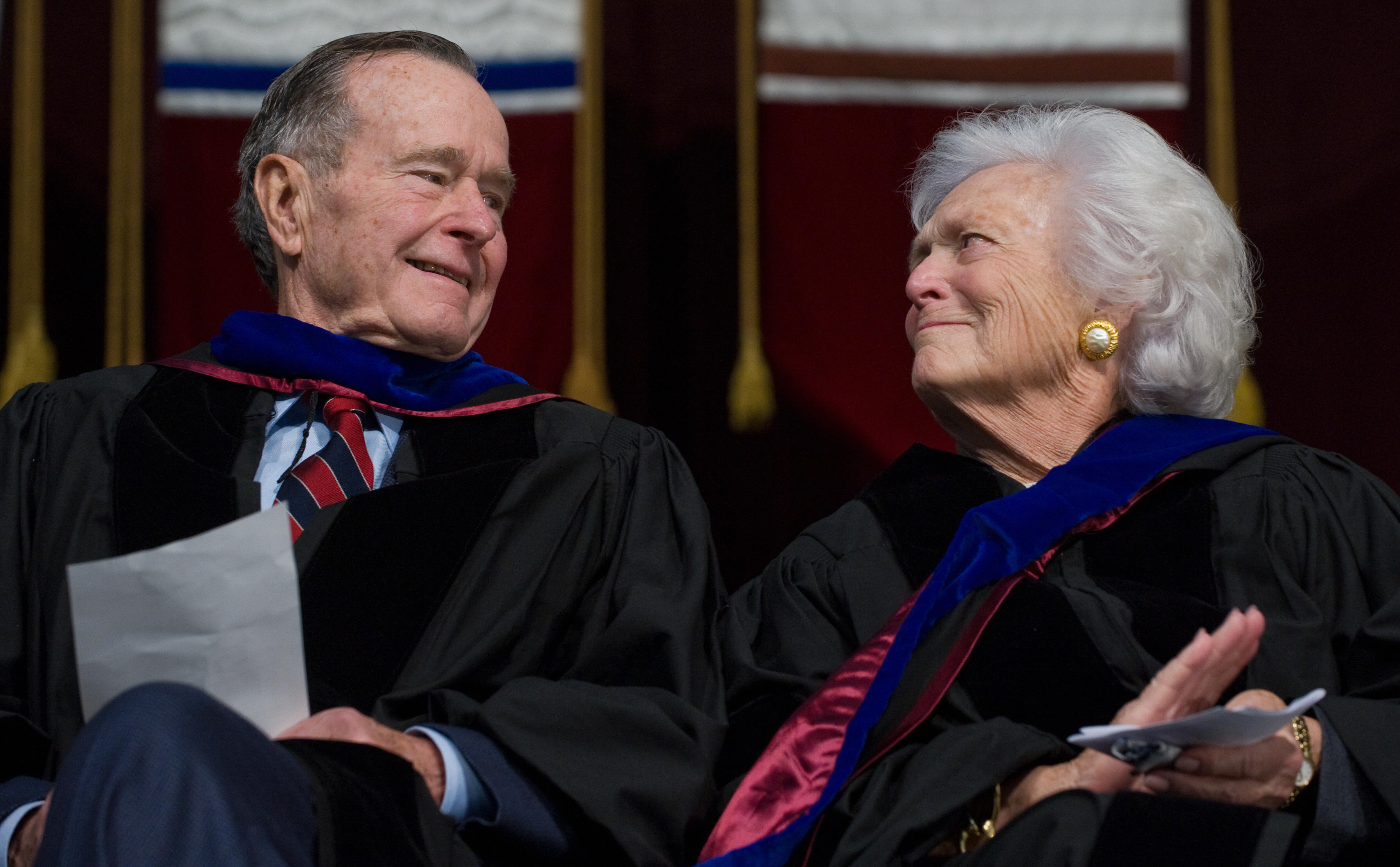 George H.W. Bush and Barbara Bush listen to George W. Bush deliver a commencement address.