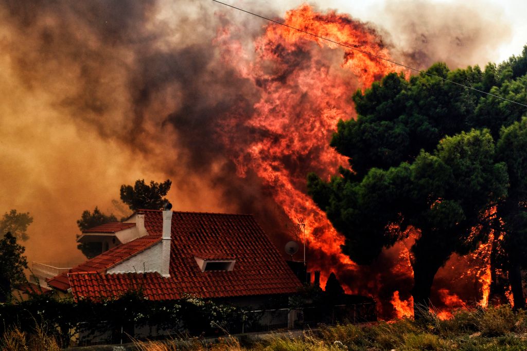 Flames reach a home near Athens, Greece, on Monday.