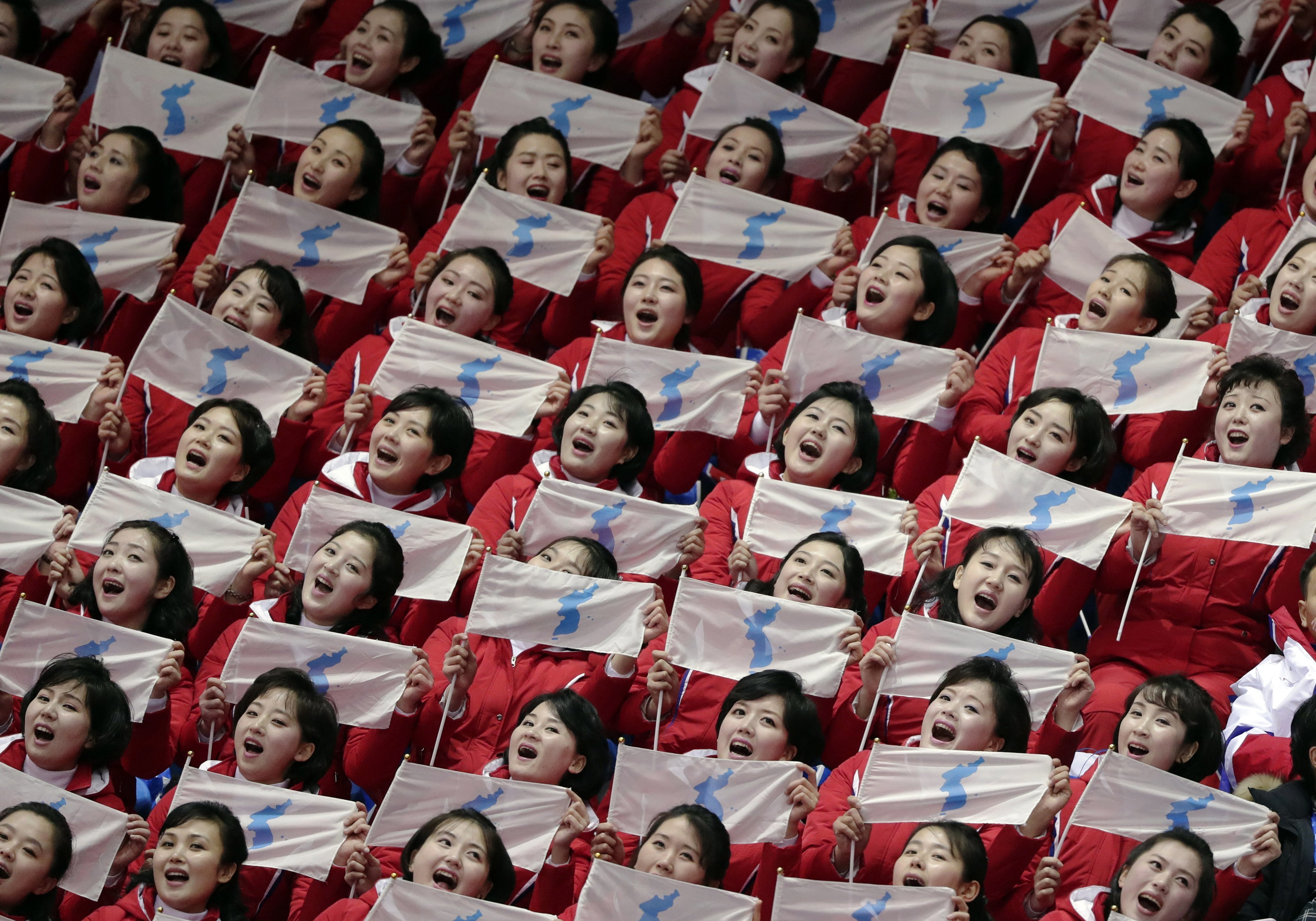North Korean supporters hold up Korean unification flags.