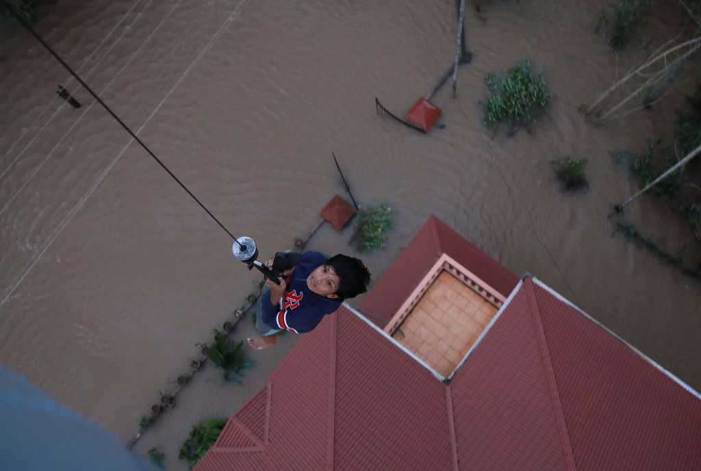 Indian People are airlifted by Navy personnel during a rescue operation at a flooded area in Paravoor near Kochi, in the Indian state of Kerala on August 18, 2018. 
