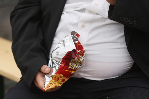 An obese person eating junk food.