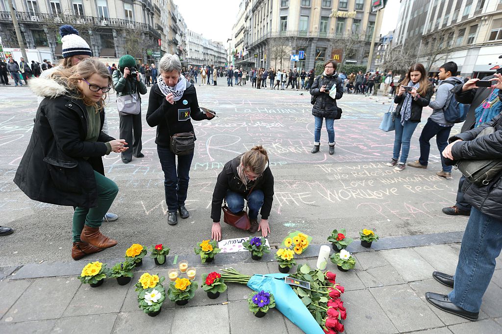 People leave messages and flowers in tribute to victims of triple bomb attacks in front of the stock exchange building in the city center of Brussels on March 22, 2016.