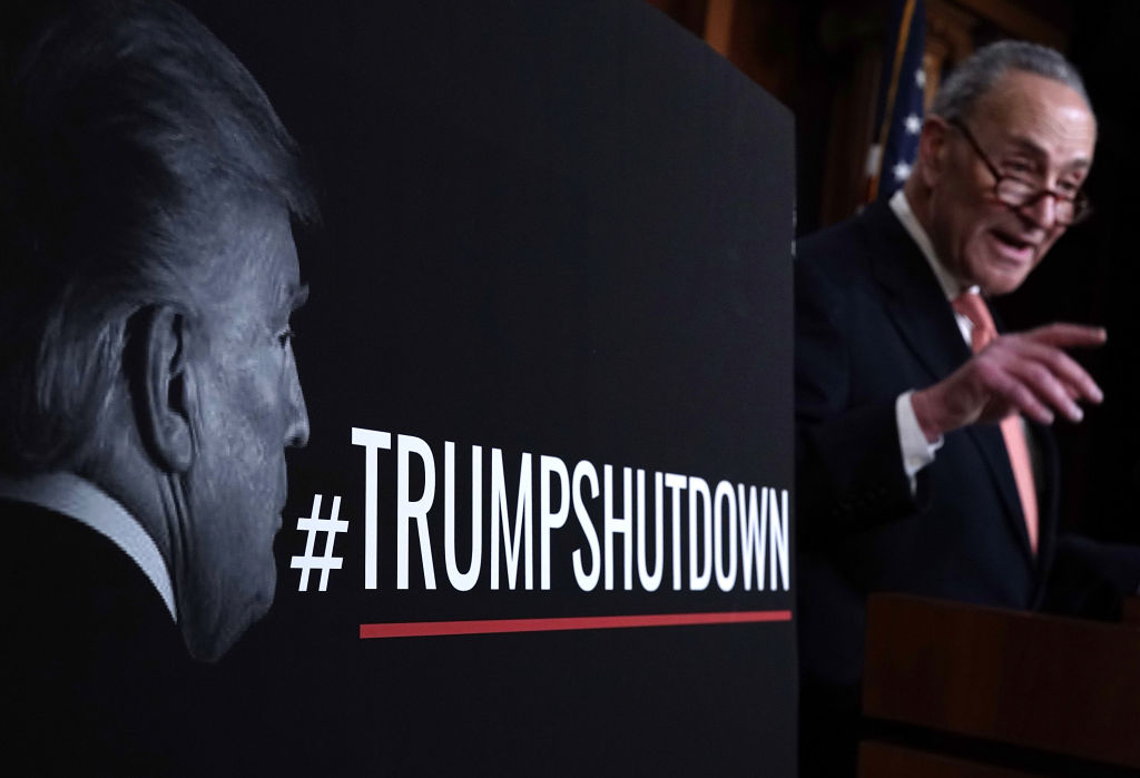  As a poster of U.S. President Donald Trump is seen in the foreground, Senate Minority Leader Sen. Chuck Schumer (D-NY) speaks during a news conference January 20, 2018 