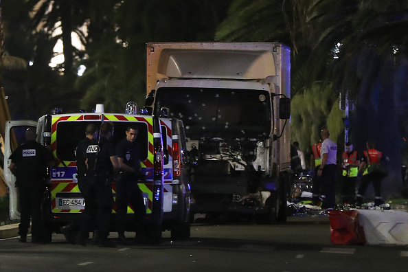 Police officers and rescued workers stand near a van that ploughed into a crowd leaving a fireworks display in the French Riviera town of Nice.