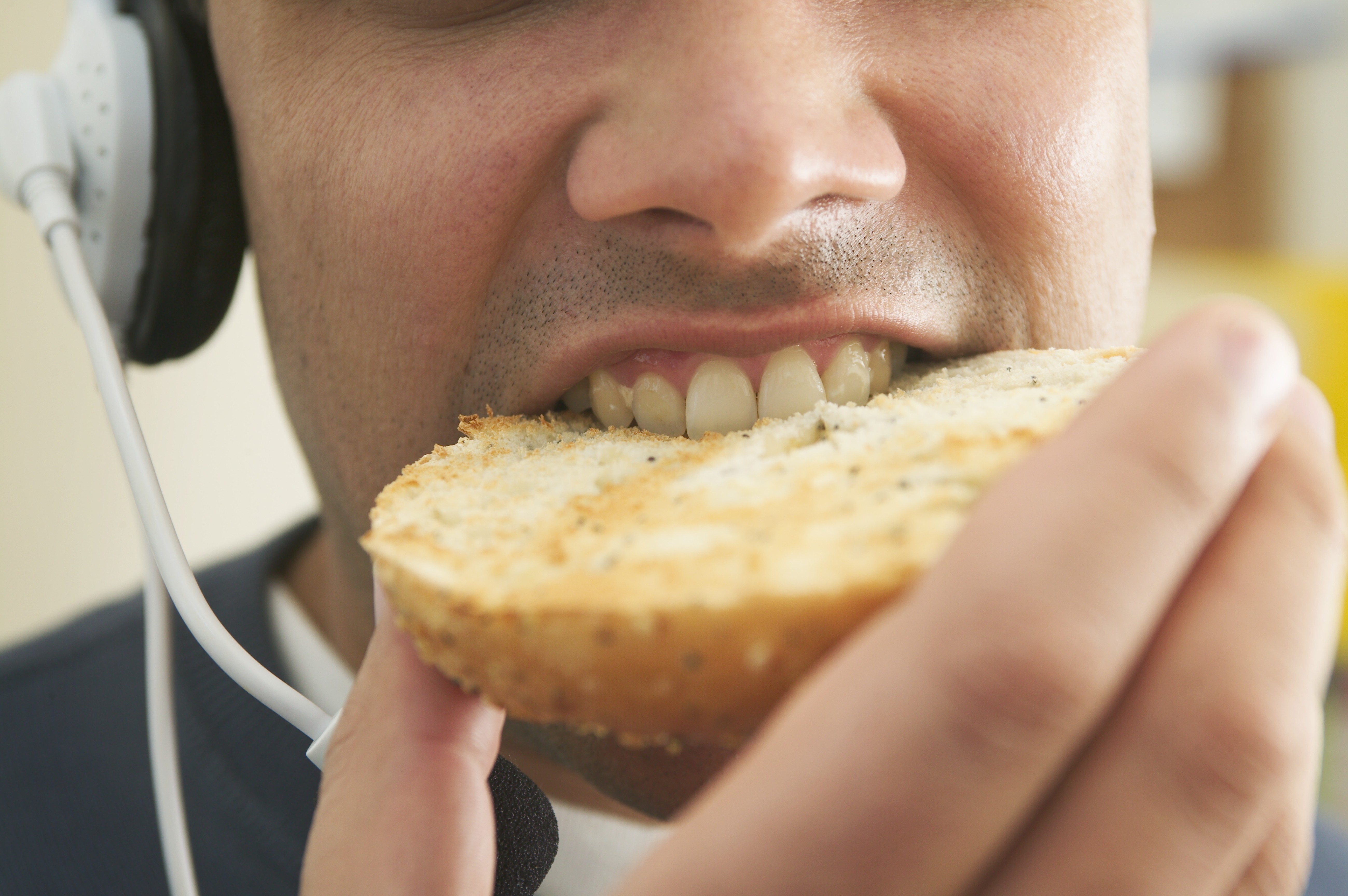 A man eating a bagel and listening to podcasts