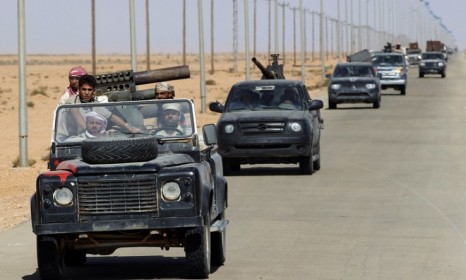 Rebel fighters drive near a destroyed military base about 20 miles east of Bani Wild, an oasis town in which some believe Moammar Gadhafi is hiding.