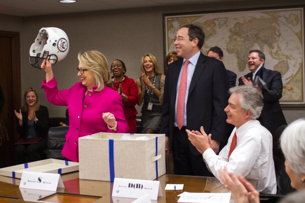 Hillary Clinton holds a football helmet gifted by Deputy Secretary Tom Nides in 2013.