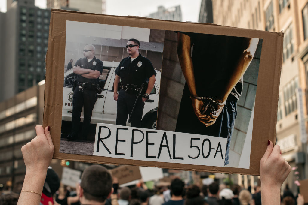 Protester holds a sign that says repeal 50-A