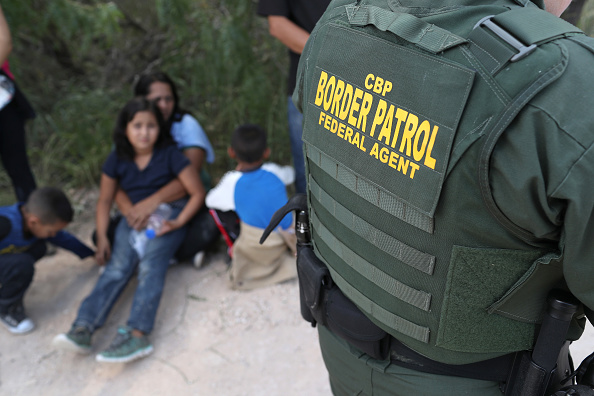 A border patrol agent takes asylum seekers into custody. 