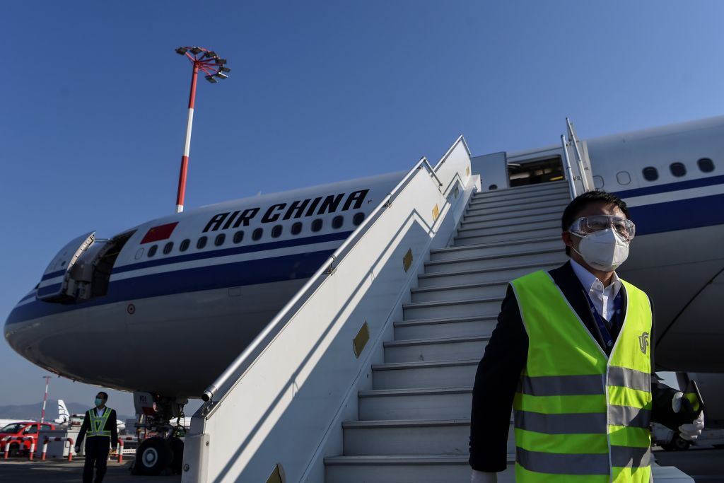 A member of staff, wearing a facemask for protective measures, disembarks from an Air China airbus carrying 500.000 protective masks at the Athens international airport, on March 21, 2020, as