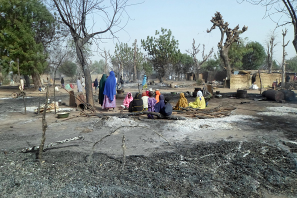 Women and children sit amid burned homes after a Boko Haram attack in Nigeria.