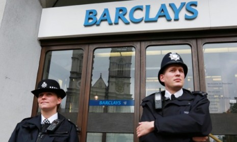 Police wait for protesters outside a London Barclays branch