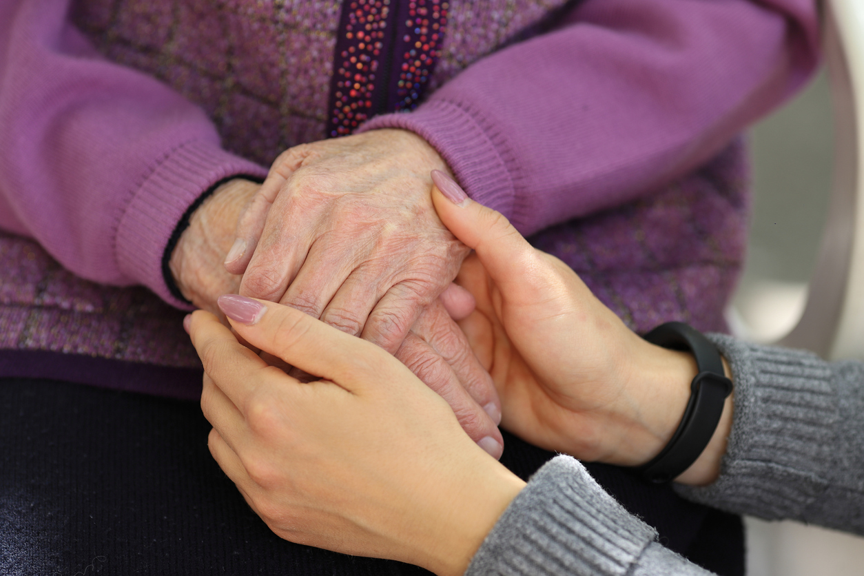 Young person and elderly person holding hands.