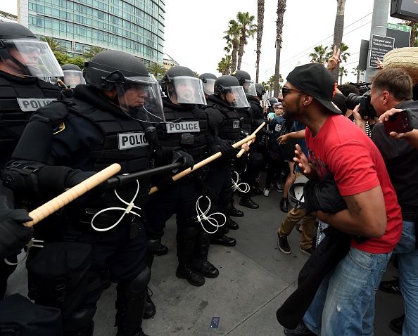Police in riot gear confront a man at a Donald Trump rally