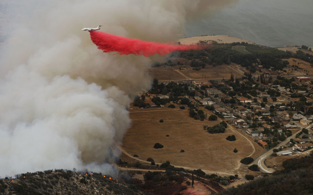 A firefighting aircraft drops fire retardant as the Holy Fire burns near homes on August 10, 2018 in Lake Elsinore, California. 