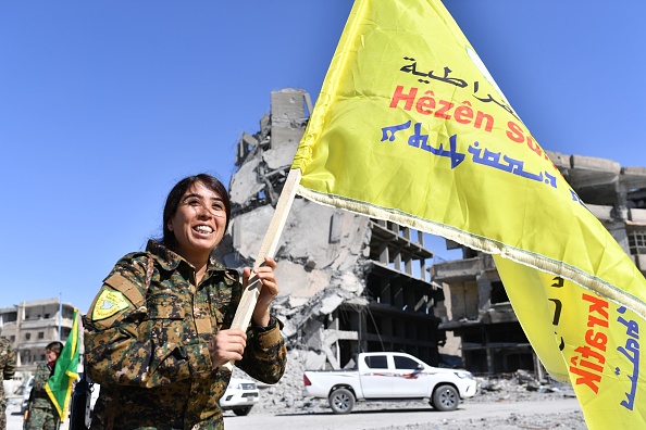 Syrian Democratic Forces commander Rojda Felat walks with the SDF flag through central Raqqa.