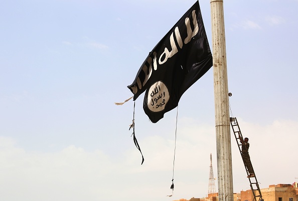 A tattered ISIS flag is taken down by an Iraqi soldier.