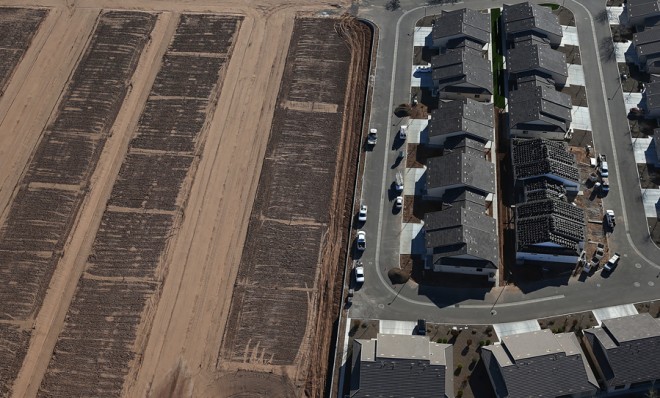 Empty parcels of land sit next to a new housing development in Mesa, Ariz., on March 6.