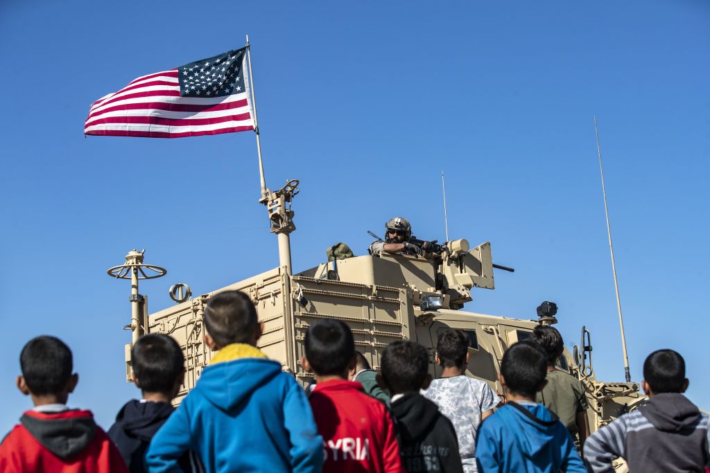 Syrian children look at U.S. troops in their vehicle.