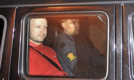 Anders Behring Breivik (left), the man accused of a killing spree in Oslo, leaves the courthouse Monday: Breivik cited the tough-on-Islam writing of Robert Spencer 64 times in his lengthy, an