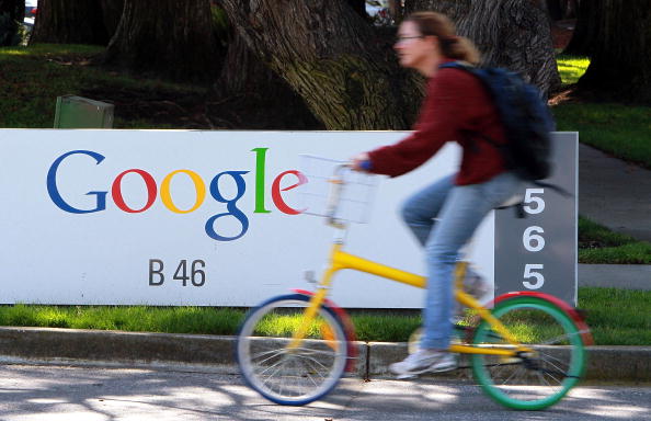 Bicyclist rides by Google sign.