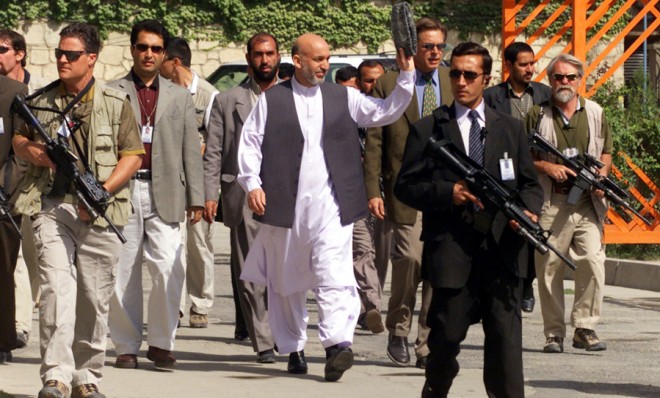 Afghanistan President Hamid Karzai waves to presidential palace workers while walking to his office in 2003.
