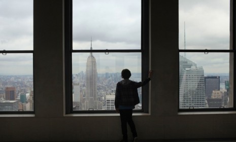 A boy looks out at the Empire State Building from the observation deck at Rockefeller Center in New York City.