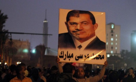 A protester in Cairo holds up a poster with the faces of current Egyptian President Mohamed Morsi and former President Hosni Mubarak as public anger mounts that Morsi is seizing too much powe