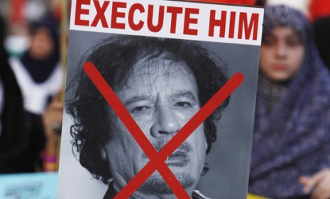 A boy holds up an &quot;Execute Gadhafi&quot; poster during a protest earlier this year