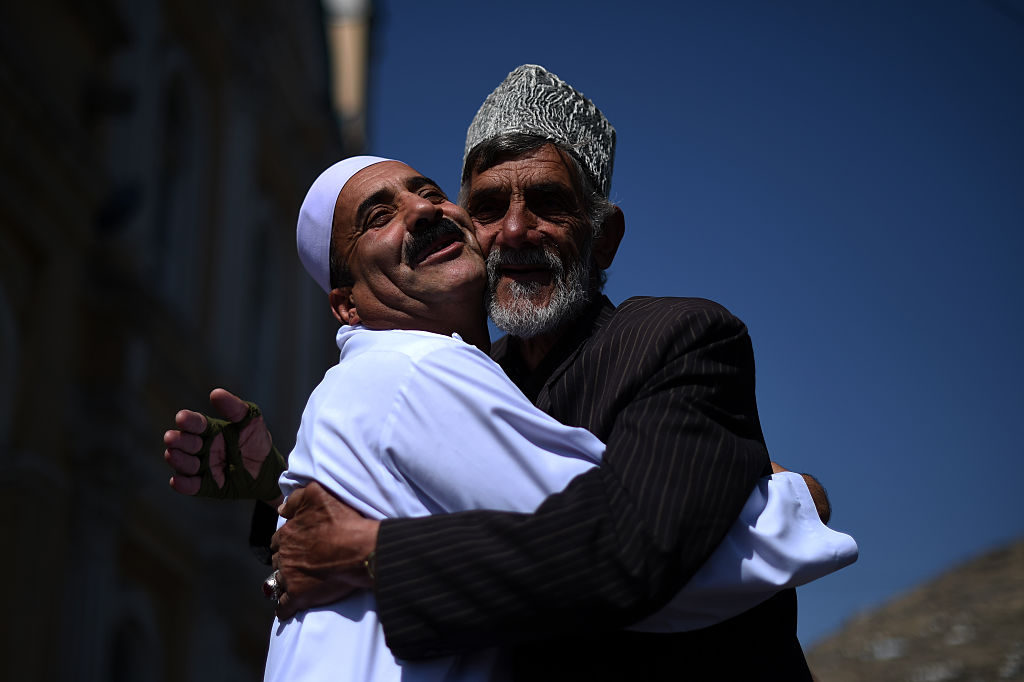 Afghan men hug each other while celebrating Eid in 2016