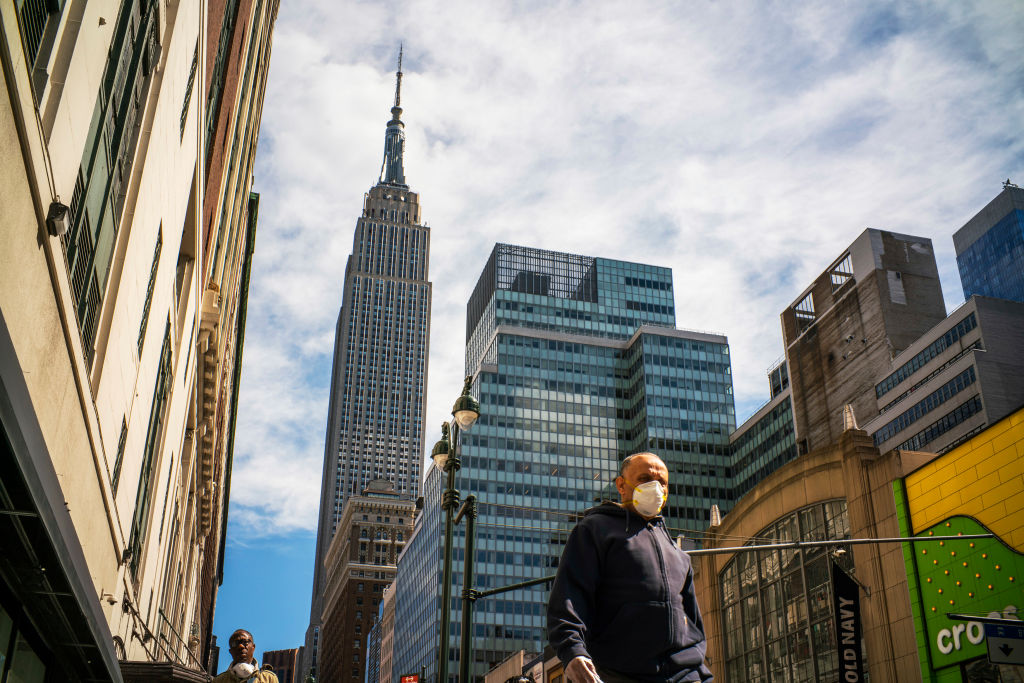 A man wears a mask while walking down a New York City street.