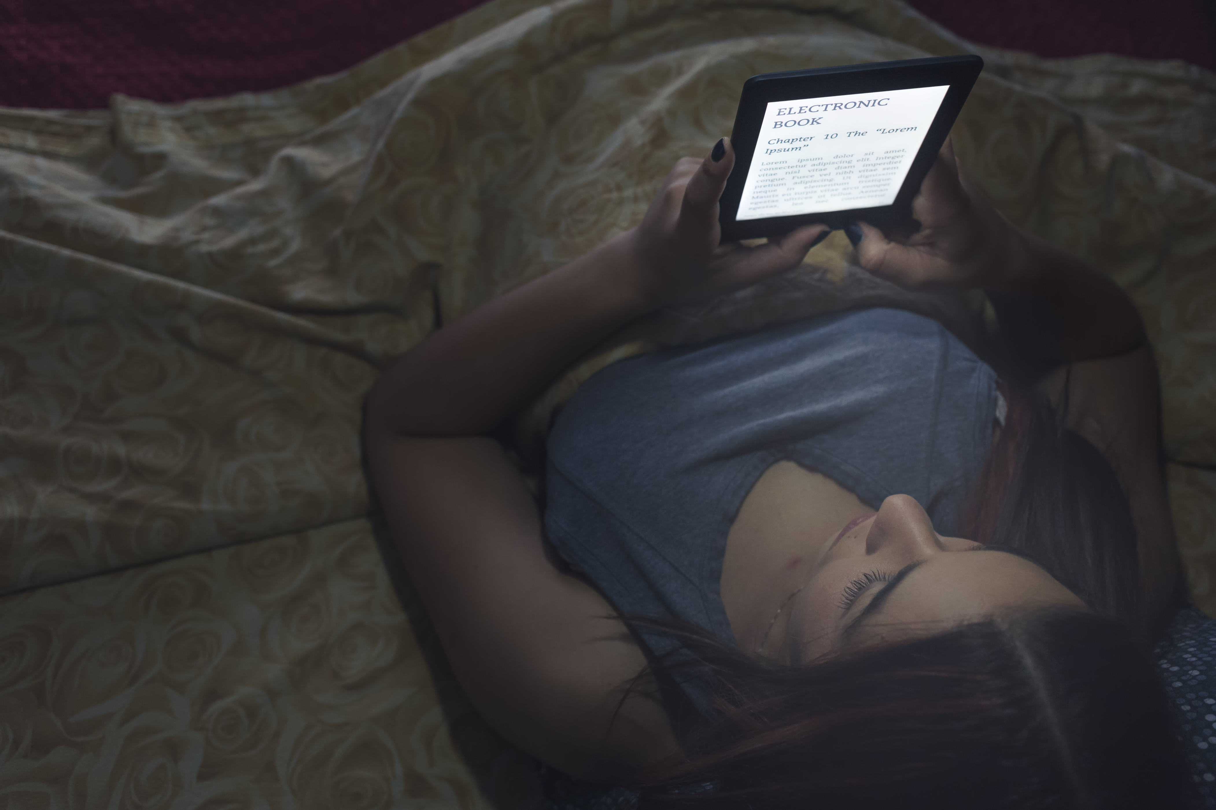 A woman reads an e-book in bed.