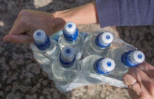 A woman opens a package of water bottles.