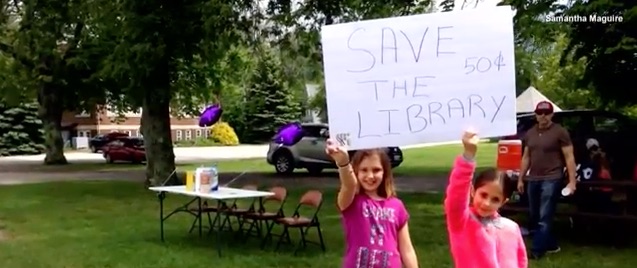 Mia Maguire and a friend hold a sign advertising her lemonade stand.