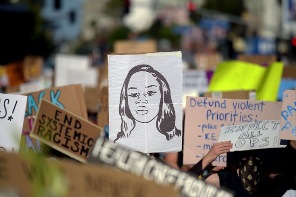 A protester marches with a picture of Breonna Taylor.