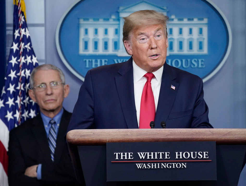 Dr. Anthony Fauci (L), director of the National Institute of Allergy and Infectious Diseases, listens to U.S. President Donald Trump speak during a briefing on the coronavirus pandemic, in th