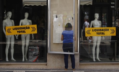 A woman arranges a display outside a Lisbon store: On Tuesday, Moody&#039;s slashed recession-plagued Portugal&#039;s government bonds to &quot;junk&quot; status.