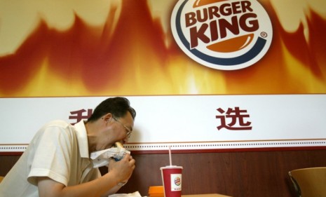 A Chinese man eats at a Burger King in Shanghai in 2005: Obesity levels in China are rising fast, but the epidemic afflicts a different segment of the population than it does in the U.S.