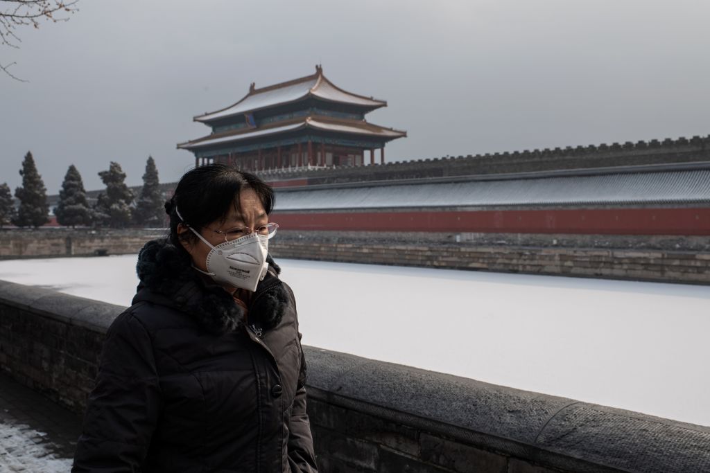 A woman wears a mask outside the Forbidden City in China.