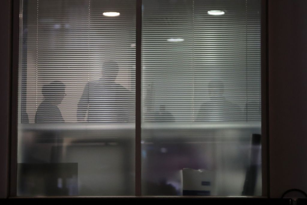The silhouettes of people are seen through blinds inside the offices of Cambridge Analytica in central London on the evening of March 23, 2018, just hours after a judge approved a search warr